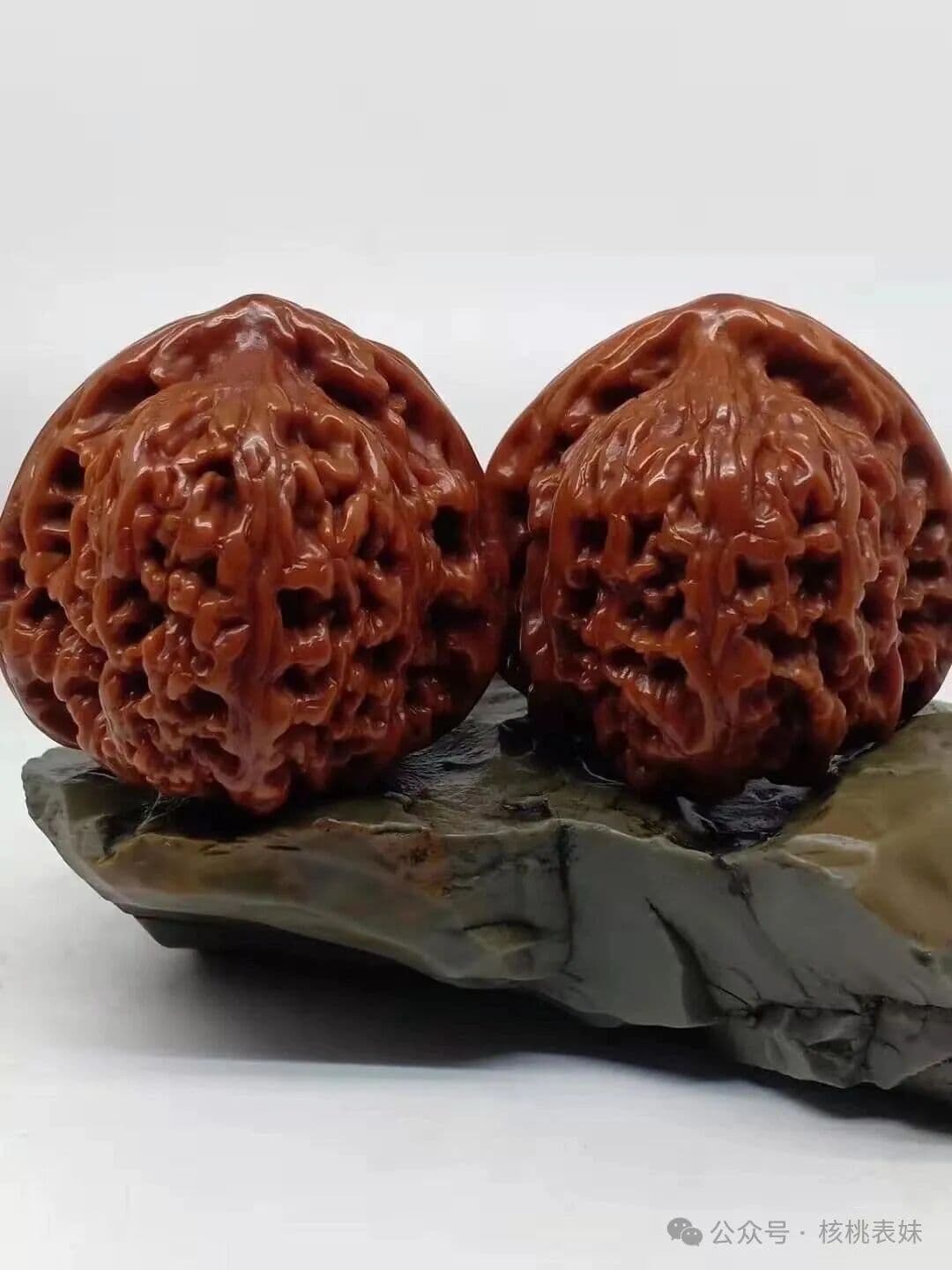 赵喜满南将石返图,两枚核桃在深色底座上并排摆放,可见整体轮廓与纹路